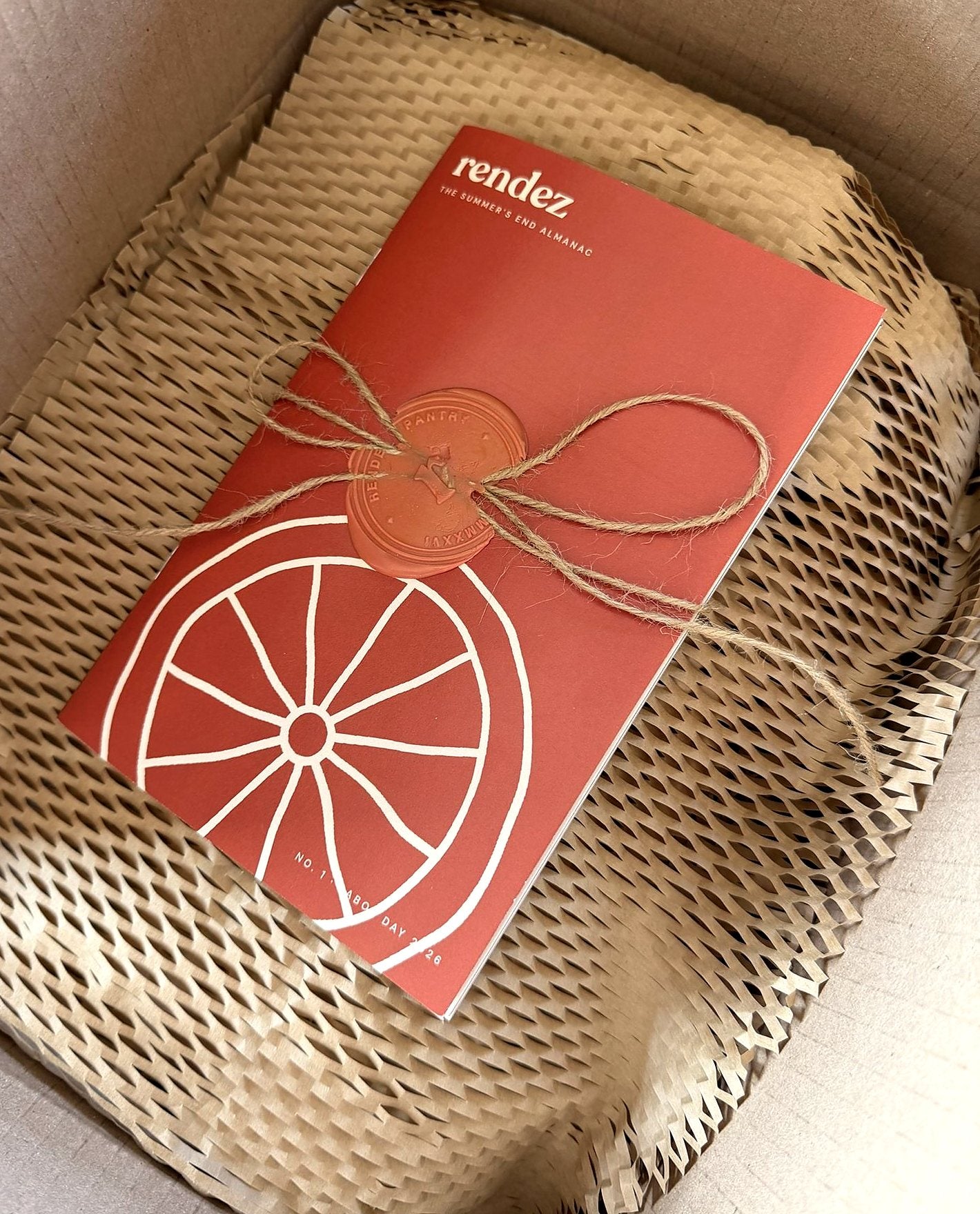 An opened Rendez box, the Almanac sealed in terracotta wax on kraft paper